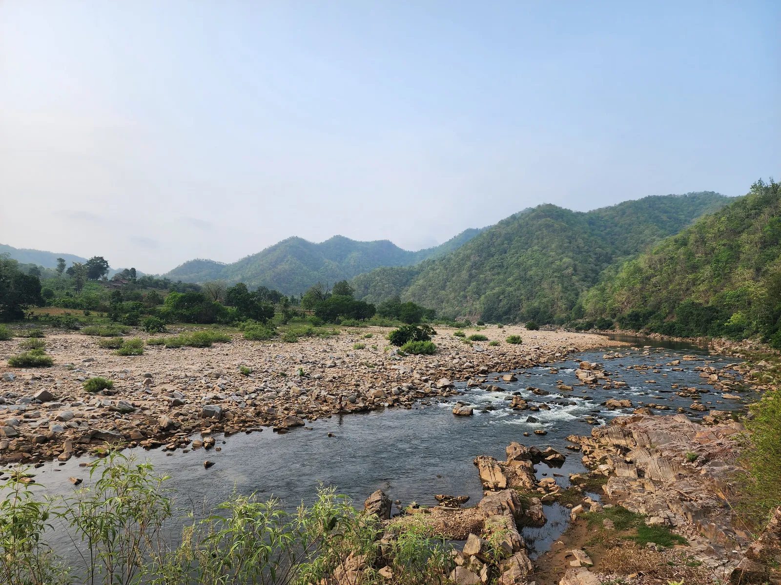 Lush green valley with a cascading waterfall at Phulwari Ki Naal, early morning mist hovering over the rocks